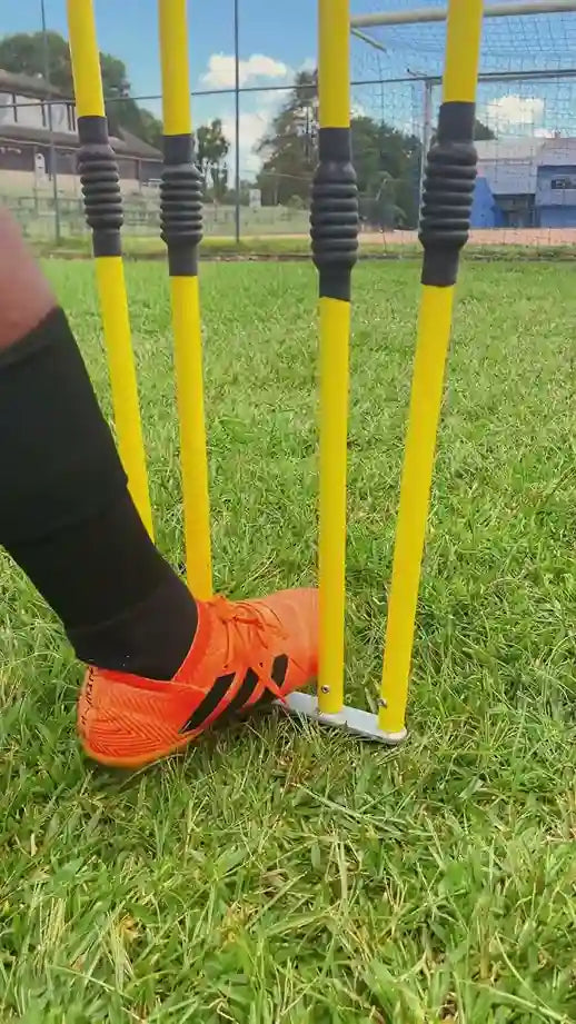 Pé com chuteira de futebol fixando a base de um boneco barreira de falta no gramado